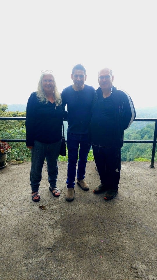 Three people standing on mountain viewpoint